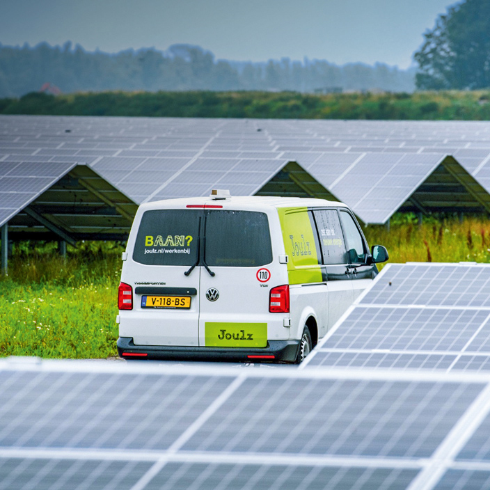 White Joulz van parked in front of solar panel array
